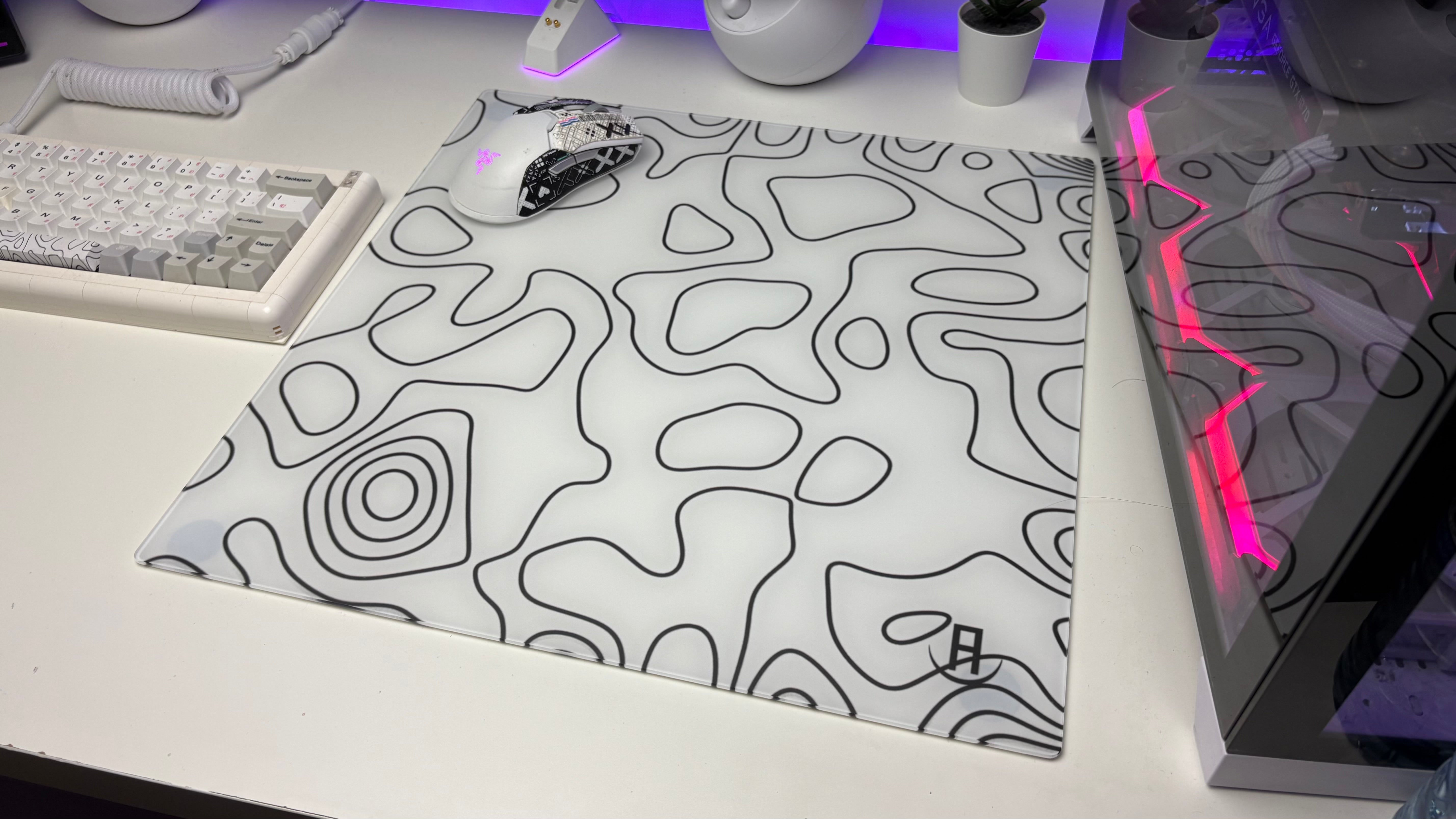 White topography glass mouse pad on desk in a gaming setup with a gaming mouse on it