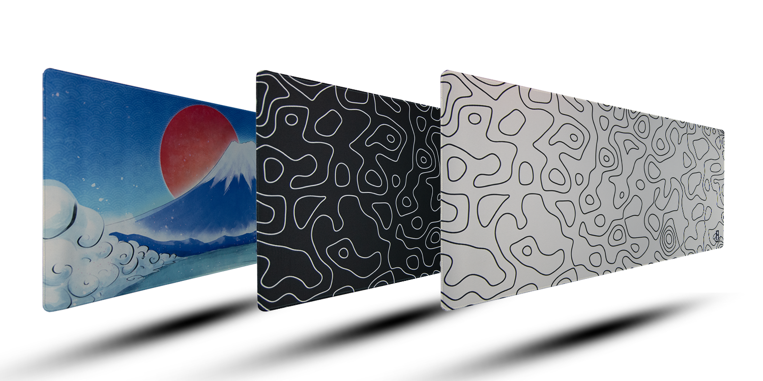 Three floating mouse pads, each with distinct designs. The left mouse pad features a scenic Japanese-style artwork with a red sun and Mount Fuji against a blue background. The middle mouse pad has a black background with a white, abstract line pattern. The right mouse pad shows a white background with a similar black abstract line pattern."