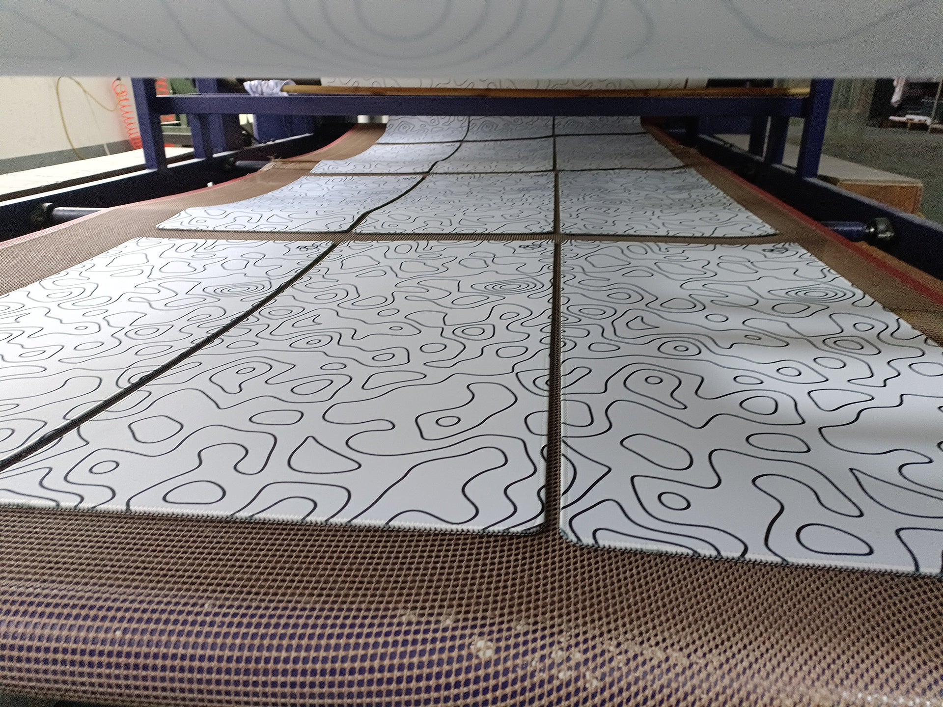 white topography gaming mouse pad on a conveyor belt in a mouse pad factory 